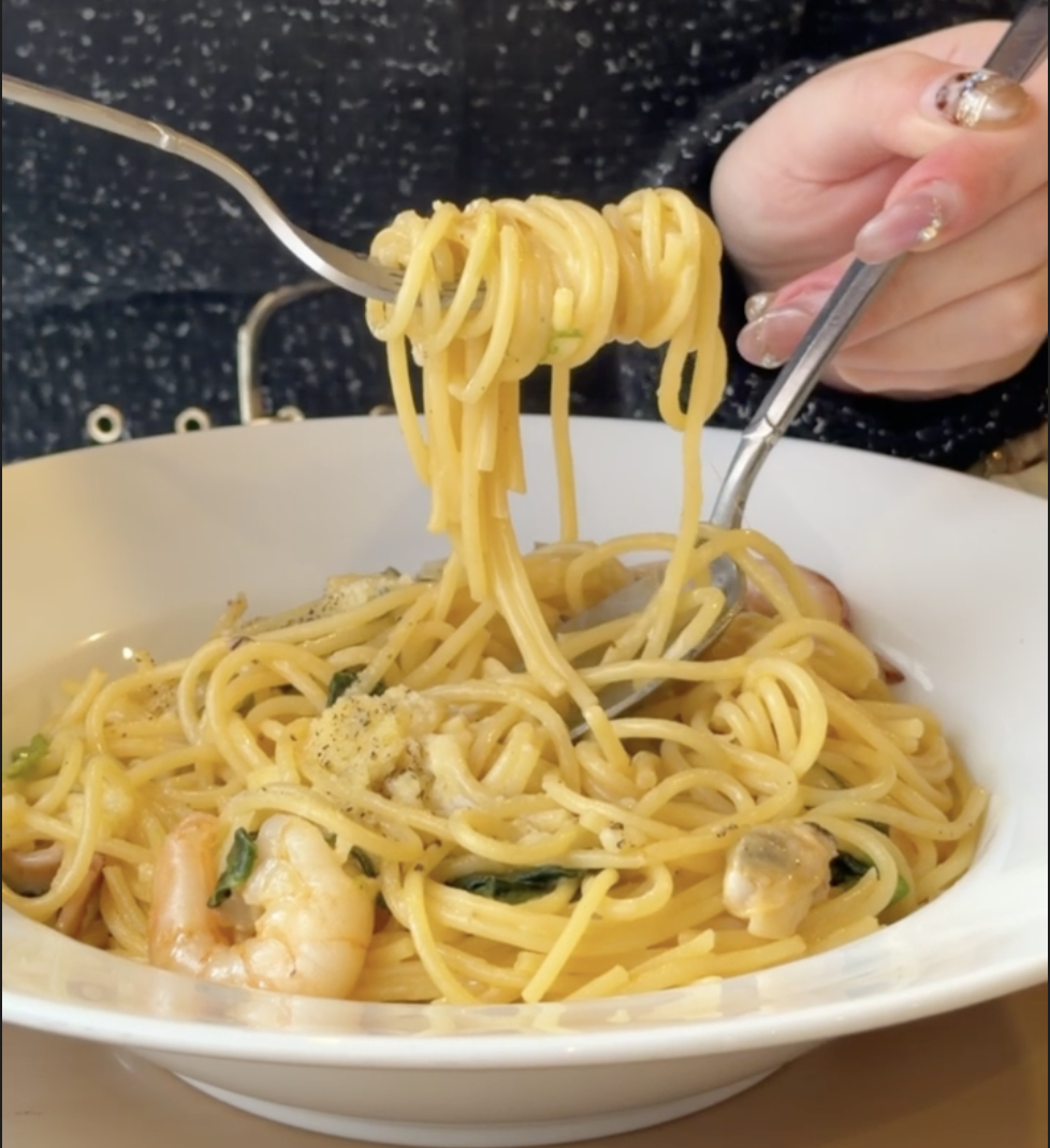 魚介のクリームパスタを味わう様子