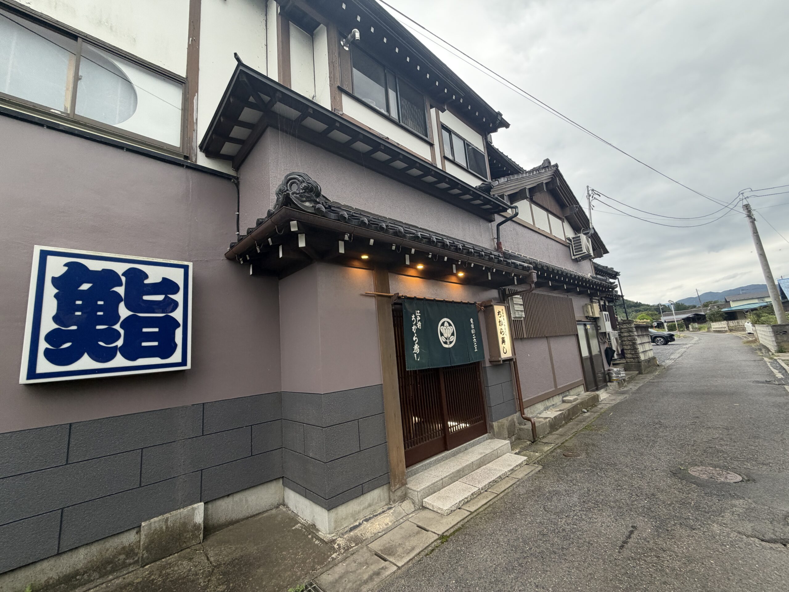 大きな鮨の看板と暖簾があるちから寿しの外観