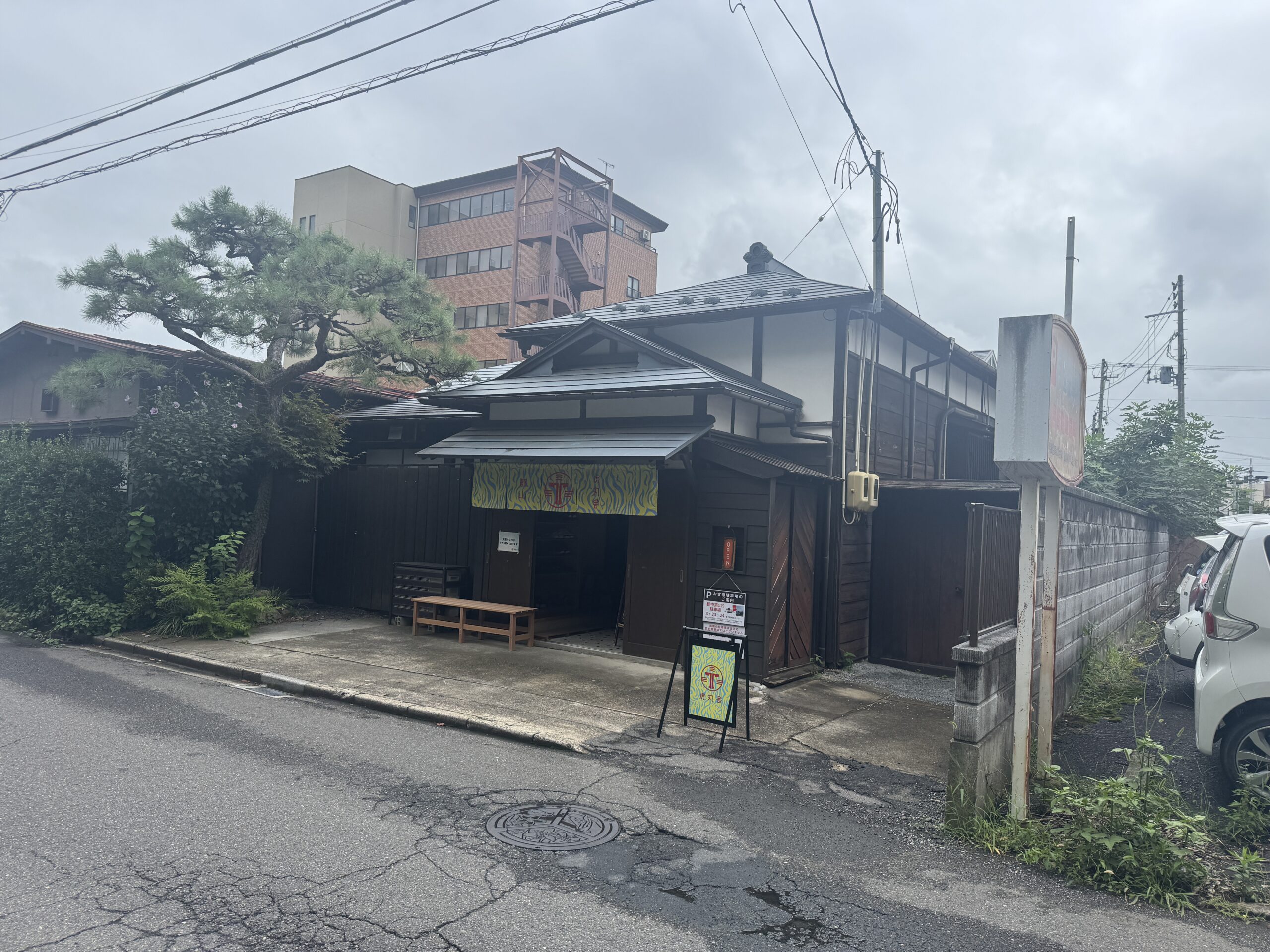 虎丸町の路地に建つ、黒い木の外壁と入口の看板が目印の古民家カフェ虎丸舎